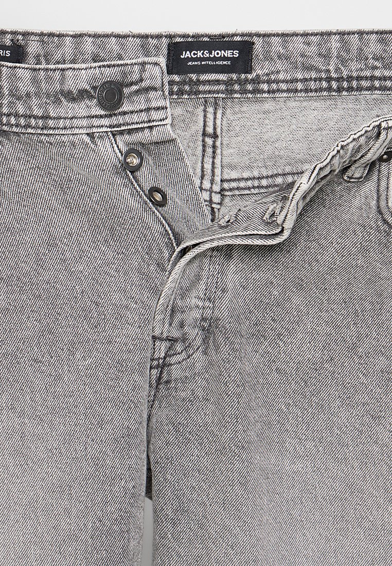 Schwarze und weiße Jeans aus Denim mit einem Knopfverschluss, versehen mit einem Etikett, auf dem "JACK&JONES" steht, und sichtbaren Nähten entlang der Nähte.