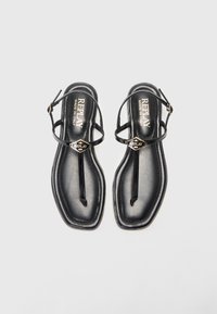 Sandalete plate negre cu design tip thong, fabricate din piele netedă. Au curele subțiri, un accent cu logo și o talpă conturată.