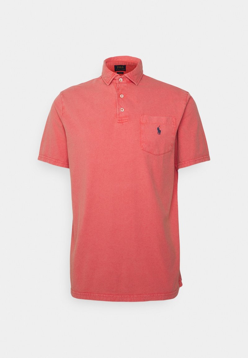 Lyhythihainen polo-paita korallivärisestä kankaasta, jossa on kolme napinläppää, kaulus, rintatasku ja pieni laivaston sininen logo taskussa.