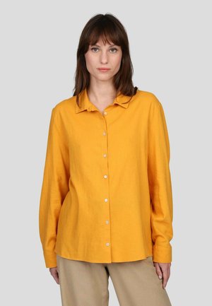 Chemise jaune à manches longues en tissu léger, avec un col classique et une fermeture à boutons sur le devant.
