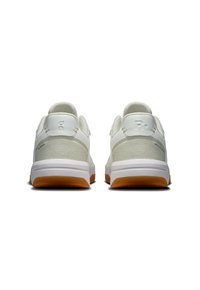 White athletic shoes with a suede and mesh upper, featuring a cushioned sole and a gum rubber outsole for traction.