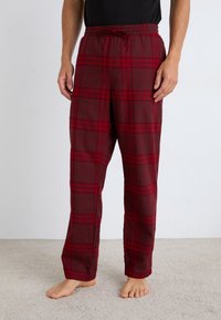 Pantalons de pyjama à carreaux rouges et gris avec une taille élastique et un cordon de serrage. Fabriqués à partir d'un tissu doux, ils présentent une coupe ample et confortable.