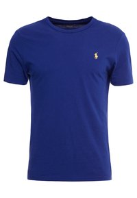 Modrá bavlněná tričko, krátké rukávy, kulatý výstřih, s malým zlatým logem na levé straně hrudi. Hladká textura, volný střih.