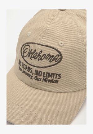Béžová kšiltovka vyrobená z texturované látky, s hnědým vyšitým nápisem "Oklahoma" a frází "ŽÁDNÉ CESTY, ŽÁDNÁ OMEZENÍ."