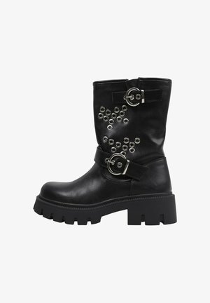 Botte en cuir noire montant jusqu'au milieu du mollet, avec une semelle épaisse à crampons, deux boucles argentées et des œillets décoratifs en argent sur la tige.