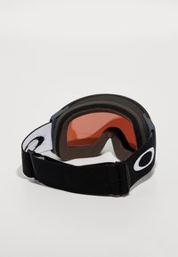 Des lunettes avec un bandeau noir et un logo blanc, dotées d'une lentille orange, d'un intérieur doux et d'un design courbé et aérodynamique.