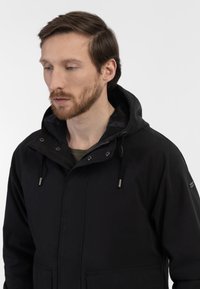 Sort hættetrøje med lynlås foran, snoretræk, store lommer og sølvfarvede metaldele. Tekstureret stof med mat finish.