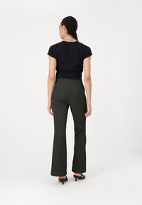Black fitted t-shirt with short sleeves and high-waisted dark green flared pants. Positioned on a plain white background.