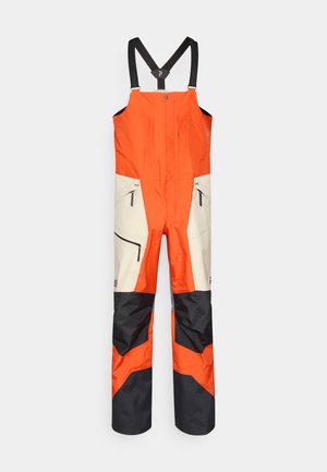 Wasserdichter Overall in Orange und Creme mit verstellbaren schwarzen Trägern, zwei mit Reißverschluss versehenen Fronttaschen und schwarzen Akzentpanelen an der Hose.