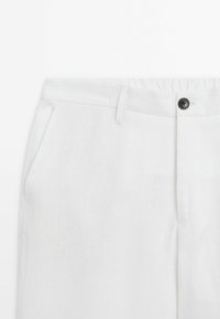 Weiße Leinenhose mit strukturierter Oberfläche, ausgestattet mit einem Vorderknopfverschluss, Gürtelschlaufen und seitlichen Taschen. Glattes Material und taillierte Passform.