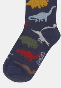 Marineblaue Socken mit verschiedenen bunten Dinosaurier-Mustern in Gelb, Rot, Grün, Blau und Weiß; aus weichem Strickmaterial gefertigt.