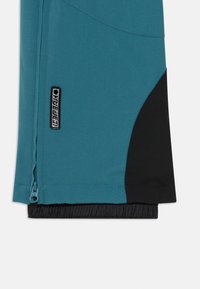 Tee groene outdoorbroek met een zwarte accent, voorzien van een zijrits en een elastische manchette. Gemaakt van een gladde, duurzame stof.