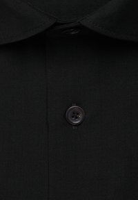 Col de chemise noir et patte de boutonnage avec un bouton noir à quatre trous visible, centré dans le cadre.