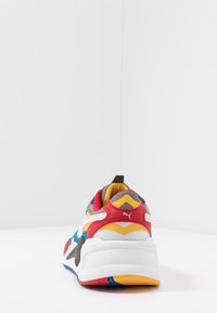 Baskets Puma avec un mélange de rouge, jaune, gris et bleu. Matériaux en maille et texturés. Semelle épaisse blanche avec des accents de couleur.