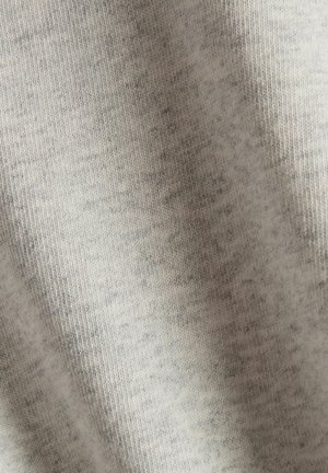 Tela de color gris claro con una textura suave, que muestra un sutil patrón jaspeado. El material parece elástico y ligero. No hay herrajes ni acentos visibles.