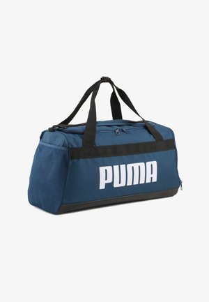 Niebieska torba sportowa Puma z czarnymi uchwytami, zamkiem błyskawicznym na górze, boczną kieszenią z siatki i dużym białym logo Puma z przodu.