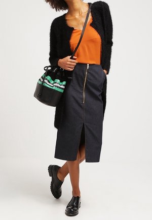 Musta teksturoitu neuletakki, oranssi satiinitoppi, tummansiniset denimmidi-hame etuvetoketjulla ja halkiolla, mustat kengät ja musta laukku vihreillä raidoilla.