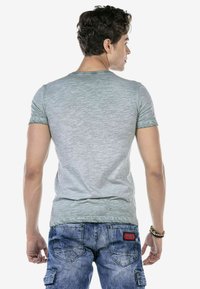 Lichtgrijze T-shirt met korte mouwen en een subtiele textuurpatroon, gecombineerd met blauwe denim shorts met achterzakken en een rood accentlogo.
