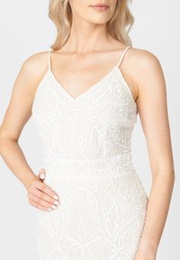 Biała sukienka z koralikami, z dekoltem w serek i cienkimi ramiączkami, ozdobiona skomplikowanym haftem kwiatowym i cekinowymi detalami. Gładka faktura materiału.