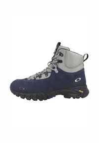 Mörkblå vandringskänga med grå detaljer, överdel i mocka och mesh, vadderad krage och robust svart Vibram-sula. Har lätta snören och öglor.