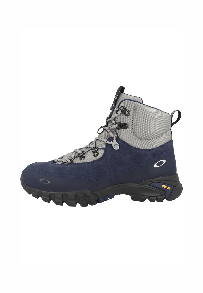 Mörkblå vandringskänga med grå detaljer, överdel i mocka och mesh, vadderad krage och robust svart Vibram-sula. Har lätta snören och öglor.