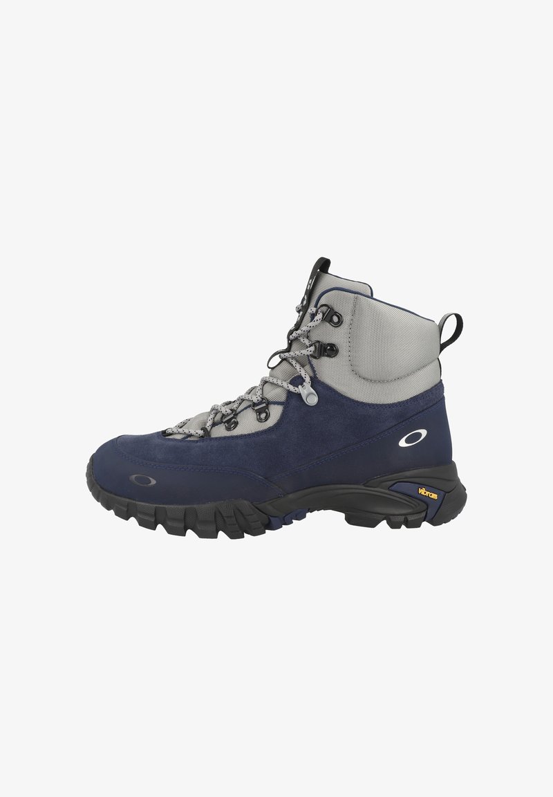 Mörkblå vandringskänga med grå detaljer, överdel i mocka och mesh, vadderad krage och robust svart Vibram-sula. Har lätta snören och öglor.