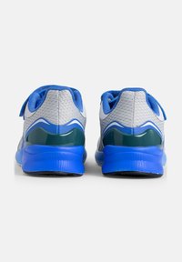 Un paio di scarpe sportive grigie e blu viste da dietro, con suole blu, fodera interna blu e dettagli neri sul tallone.