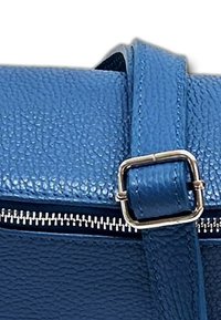 Blauwe leren handtas met een gestructureerd oppervlak. Heeft een rits in zilverkleur en een rechthoekige gespsluiting voor aanpassing.