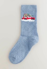 Ciorap fuzzy albastru cu o suprafață texturată. Prezintă un design cu o mașină roșie și un copac verde. Modelul tricotat în alb se află sub mașină.
