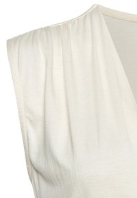 Top color crema con escote drapeado y textura suave y lisa. Presenta hombros fruncidos y un diseño minimalista.