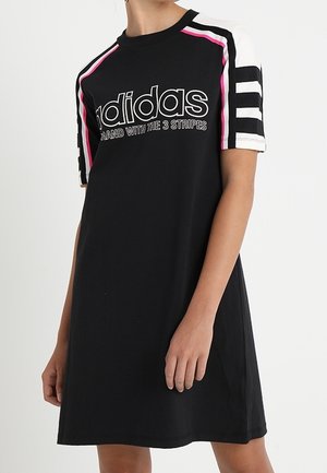 Czarna sukienka t-shirt Adidas z białymi i różowymi paskami na ramionach i rękawach, z napisem „Marka Adidas z trzema paskami”.