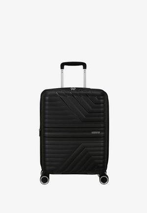 Valigia rigida nera con texture a coste, linee diagonali in rilievo, due ruote, manico telescopico in alluminio e chiusura con zip.