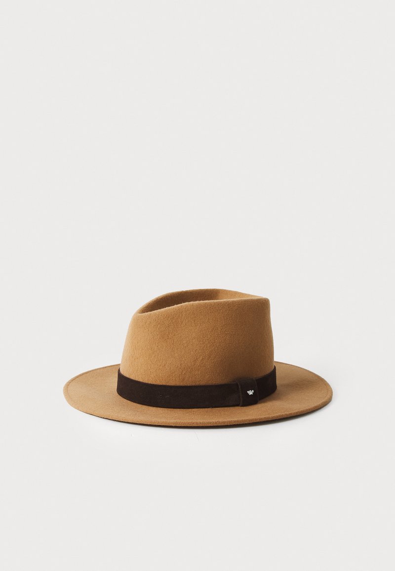 Chapeau en feutre brun avec un large bord, orné d'un bandeau en daim brun foncé et d'un petit détail métallique. Structuré, avec une forme légèrement asymétrique.