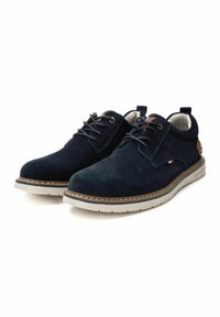 Zapatos de ante azul marino con punta redondeada, diseño de cordones, suela blanca en contraste y detalles en cuero marrón en el talón y la lengüeta.