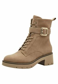 Bottines en daim marron clair avec un devant lacé, une lanière réglable avec boucles et un talon épais. Présente une semelle texturée avec des rainures prononcées.