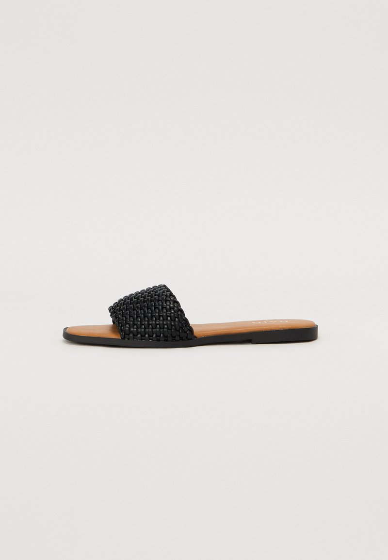 Sandale à glissière tissée noire avec une semelle plate, dotée d'une sangle texturée et d'un semelle en cuir lisse. Design minimaliste et style ouvert.