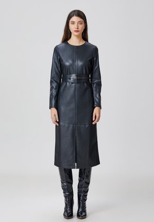 Robe longue en cuir noir à manches longues avec un col rond et une ceinture. Présente une silhouette droite, une fente à l'avant et une texture lisse.