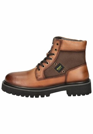 Botte cheville en cuir marron et tissu avec semelle en caoutchouc noire, design à lacets, œillets en métal et patch logo sur le côté.