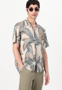 Κοντομάνικο πουκάμισο σε ελαφρύ ύφασμα, με σχέδια πράσινων και πορτοκαλί φύλλων σε μπεζ φόντο, με άνετη γραμμή και ανοιχτό γιακά.