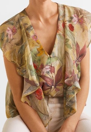 Blouse à imprimé floral avec des manches à volants, présentant un col en V. Les couleurs incluent le jaune, le vert, le rouge et le rose, avec une texture douce et transparente.