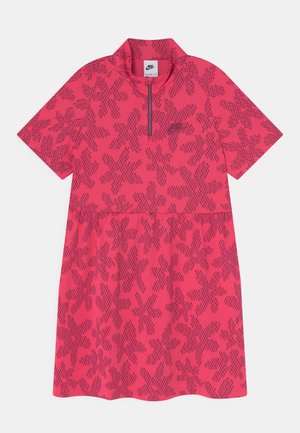 Lyserød Nike-kjole med korte ærmer, prydet med et lilla geometrisk blomsterprint og en lynlåsskrave foran.