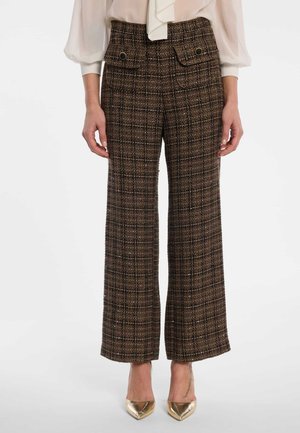Brown plaid wide-leg pants with front buttoned flap pockets worn with a cream blouse and gold pointed high heels.