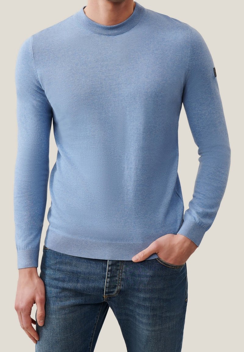 Pullover azzurro chiaro a girocollo realizzato in un materiale a maglia fine, con maniche lunghe e polsini a coste, abbinato a jeans scuri.