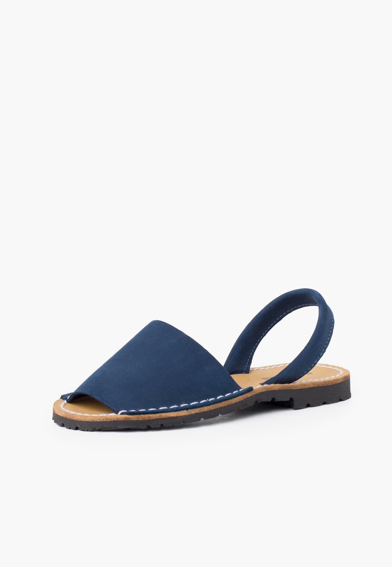 Granatowe zamszowe sandały z otwartym palcem, mające skośny przód, tylny pasek oraz przeszycia na brązowej gumowej podeszwie.