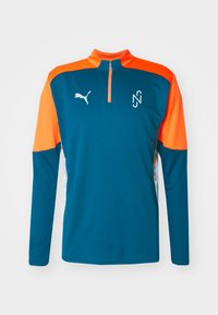 Maglietta sportiva a maniche lunghe color teal con dettagli arancioni, scollatura a mezza zip e tessuto testurizzato. Presenta un logo bianco sul petto.
