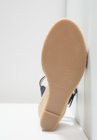 Semelle d'une sandale compensée beige avec des motifs géométriques de la semelle, taille 37, et le nom de la marque "Tamaris" embossé près du talon.