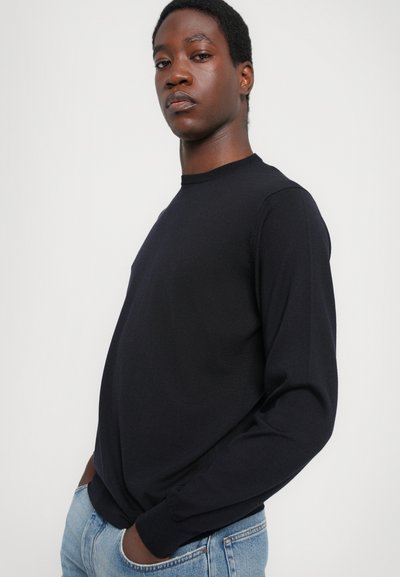 Black long-sleeve T-shirt made of soft fabric, featuring a crew neckline and fitted cuffs, paired with light blue denim jeans.