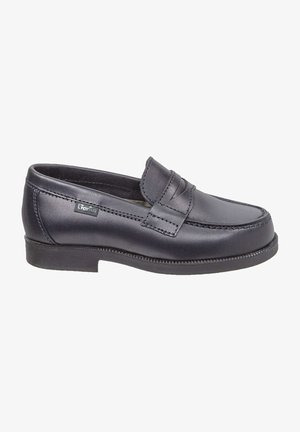 Mocasín de cuero negro con punta redondeada, correa en la parte superior y costuras en contraste. Suela de goma baja que proporciona estabilidad y comodidad.