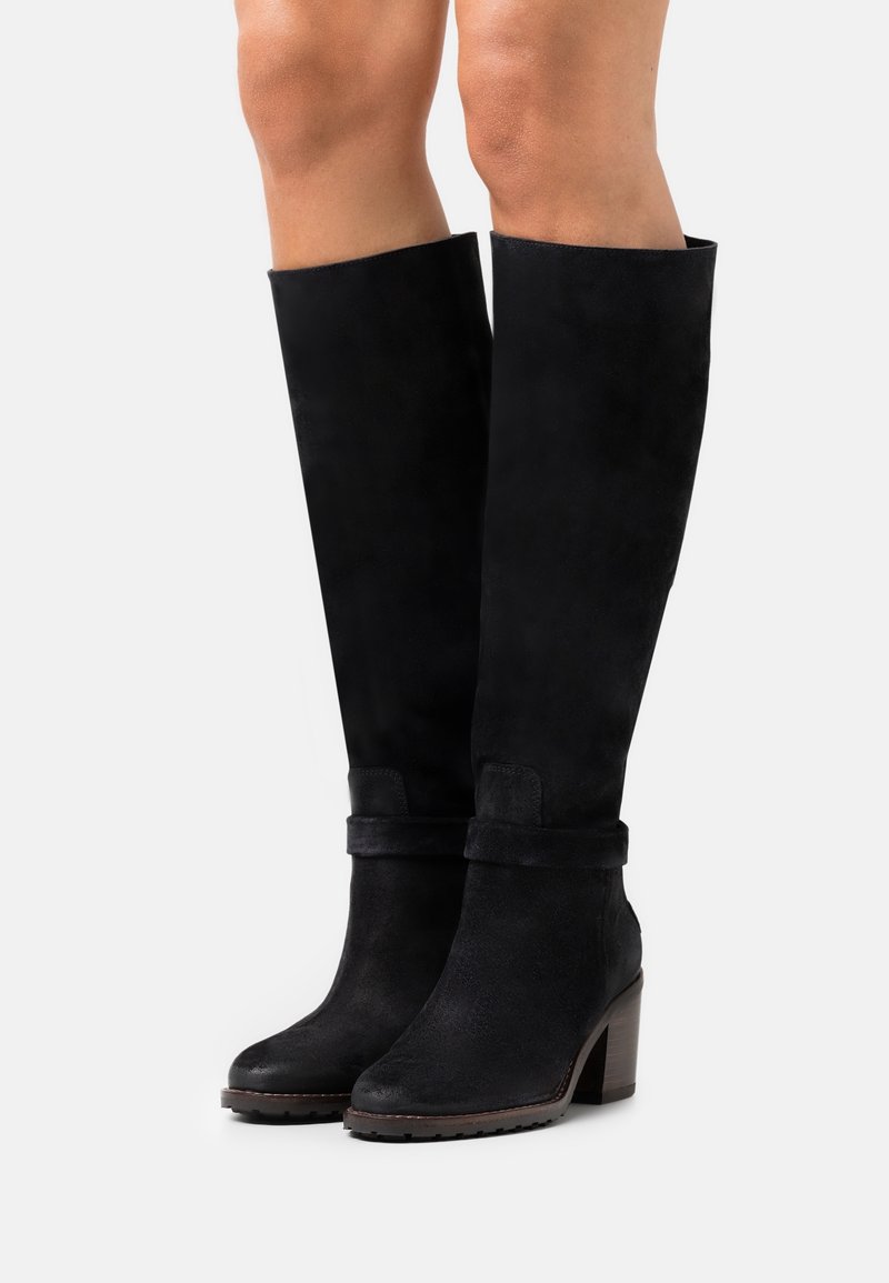 Bottes montantes en suède noir avec un talon épais, dotées d'un revers plié et d'une texture lisse, offrant une apparence élégante.