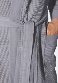 Light gray bathrobe featuring a textured waffle weave and smooth fabric. Includes a tied belt and side pockets for functionality.